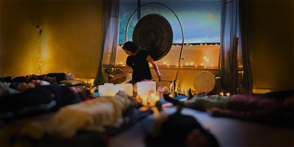 Natalie Grace facilitating a sound bath with large gong in background and people lying down in foreground